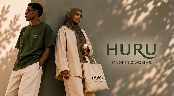 Man in a deep green HURU T-shirt and a woman in a sand linen shirt and headscarf leaning on a wall in dappled palm shade