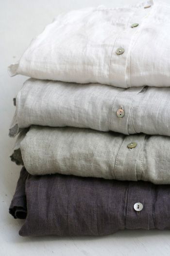Four linen shirts folded in a stack from white to charcoal