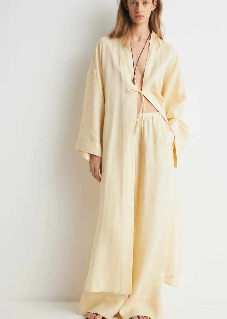 Woman in a pale butter-yellow linen shirt and wide trousers
