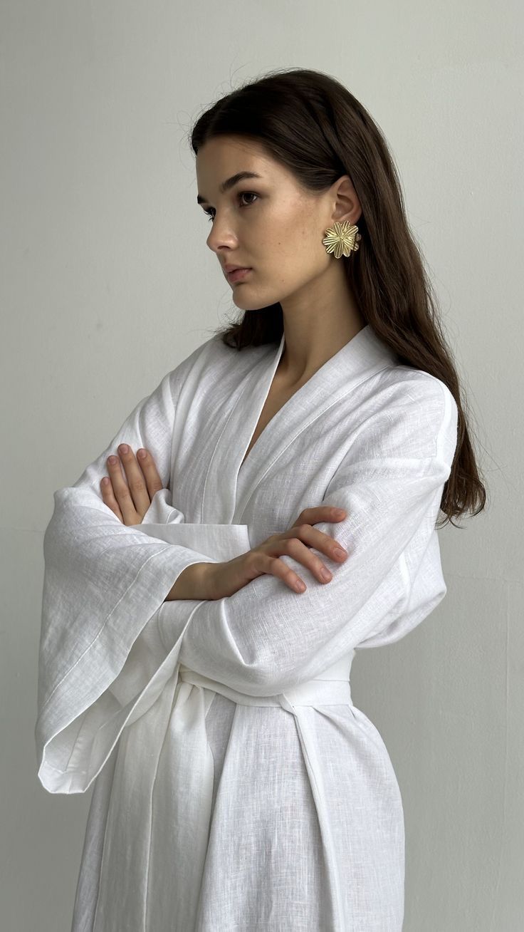 Woman in a white linen wrap robe with her arms folded